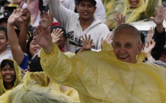 Pope Francis arrives in Tacloban, the Philippines, on Jan. 17, 2015, as a rain-drenched but lively crowd wearing yellow and white raincoats welcomes him to the typhoon-ravaged city. (AP/Bullit Marquez)